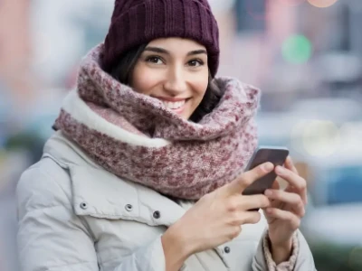 Ciepło ubrana w czapkę, szalik i kurtkę kobieta uśmiecha się