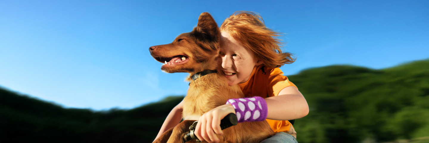 Happy child embracing their dog outdoors, suggesting pet fur as an allergy trigger