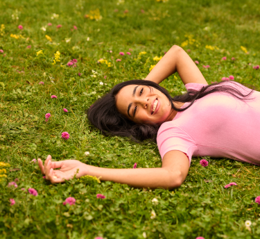 Woman relaxing in a field of flowers, carefree and free from allergy symptoms.